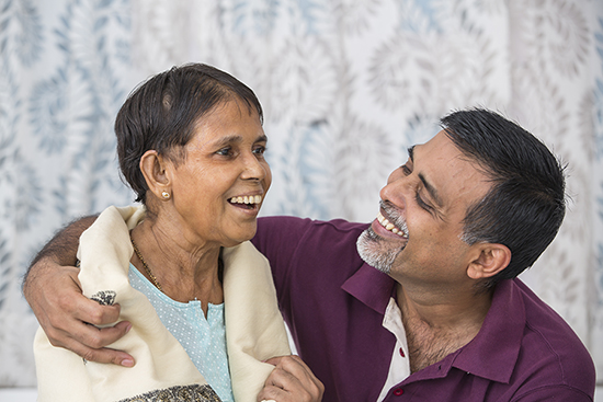 Smiling elderly woman accepts assistance from her adult son.