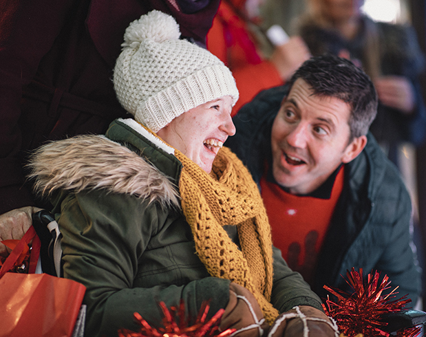 A side-view shot of a father and daughter looking at Christmas decorations on a city street, they are wearing warm Christmas​ clothing.